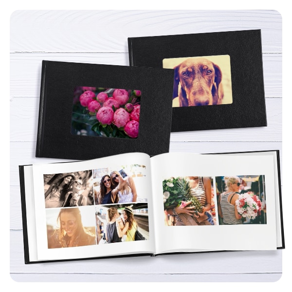 Three photo books. The two books on top are closed and show peonies on one cover and a dog on the other cover. The photo book beneath them is opened to a spread showing pictures of friends.
